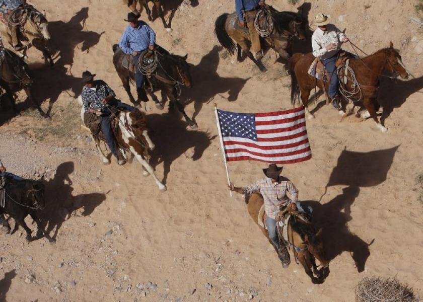 In this April 12, 2014, file photo, the Bundy family and their supporters fly the American flag as their cattle is released by the Bureau of Land Management back onto public land outside of Bunkerville, Nev.